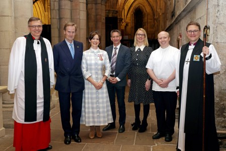 Seven people standing beside each other in a church, smiling at the camera.