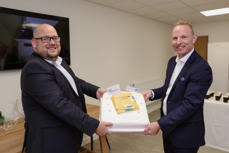 A photograph of two men holding a cake.