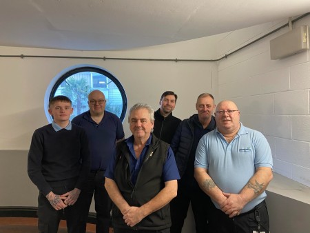 A group of 6 men wearing uniform blue shirts 