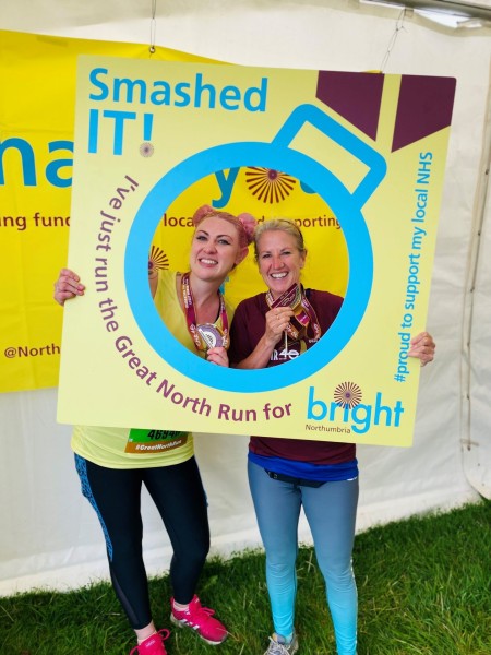 A photograph of two people using a selfie frame, they are each holding a medal.