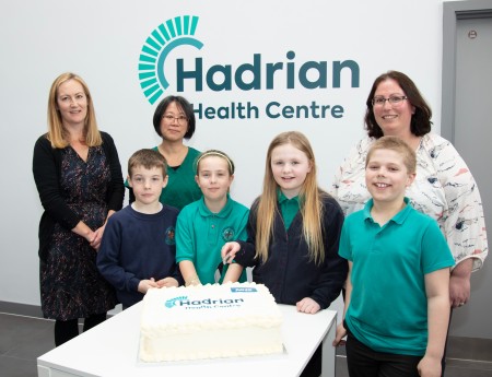 A group of children and adults cutting a cake.