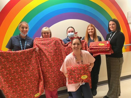 Six women standing on the children's ward holding the blankets.