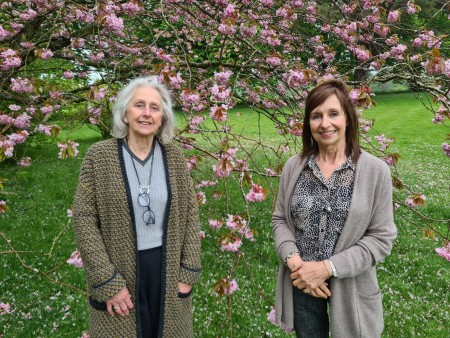 Two women standing in front of a blossom tree.
