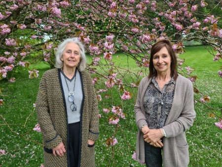 Two women standing in front of a blossom tree.