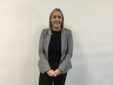 A woman with blonde hair wearing a grey blazer.