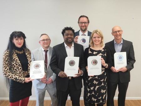 A photograph of six people smiling while holding certificates.