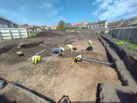 Five people digging up the ground.