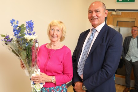 A man and a woman, the woman is holding a bunch of flowers.