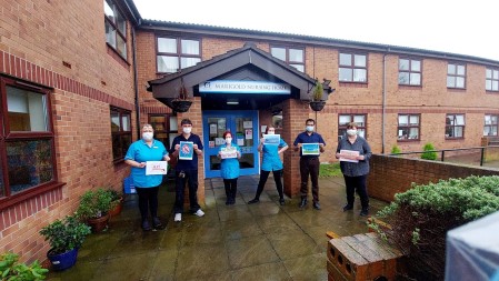 A photograph of six people standing outside holding posters.