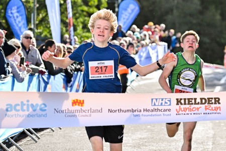 A boy crossing the finish line of a race.