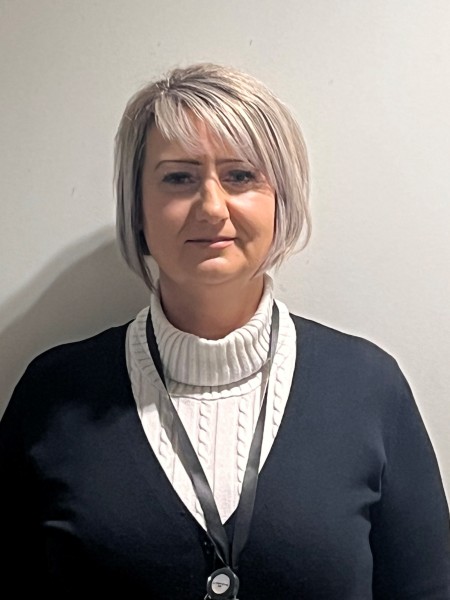 Woman with blonde hair wearing white shirt and black cardigan 