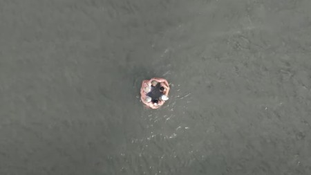 A birds-eye shot of a group of people huddled together in the sea.