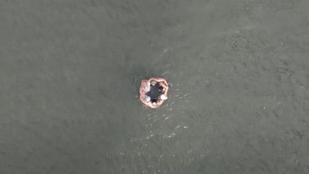 A birds-eye shot of a group of people huddled together in the sea.