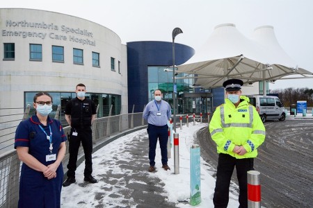 A photograph of staff outside a hospital with a police officer.