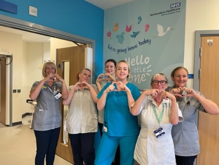 A group of women making hearts with their hands.