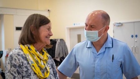 An elderly woman smiling with a male member of staff.