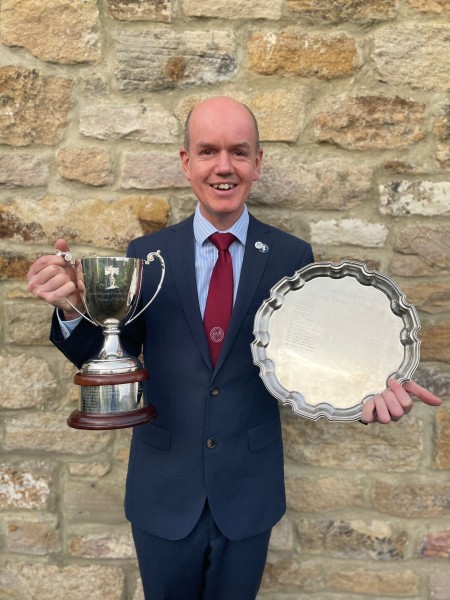 A man holding two awards.