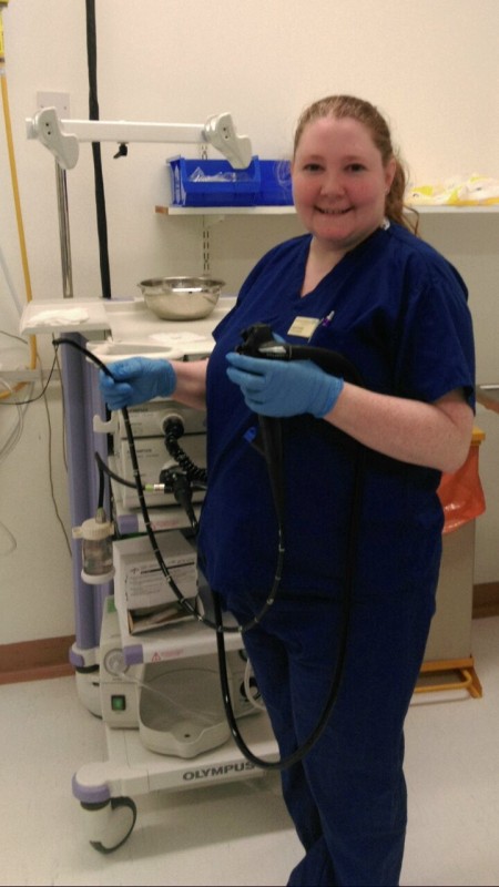 A portrait of a woman in scrubs. She is holding some medical equipment.