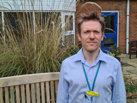 A photograph of a male standing outside.