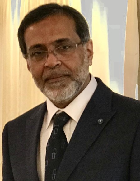 A man with dark hair a glasses wearing a suit.