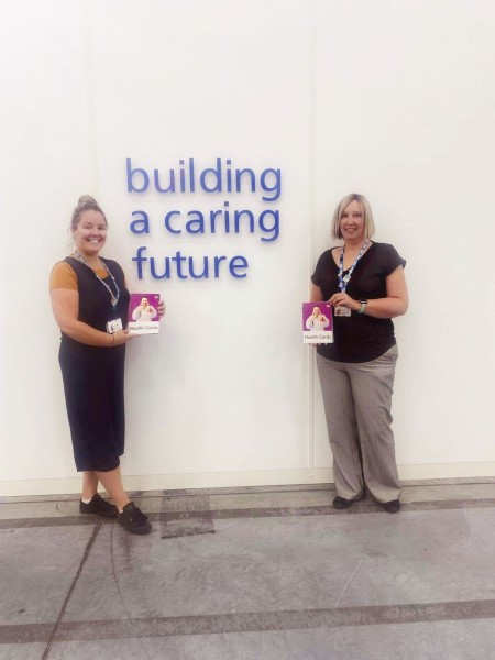 Two woman holding health cards.