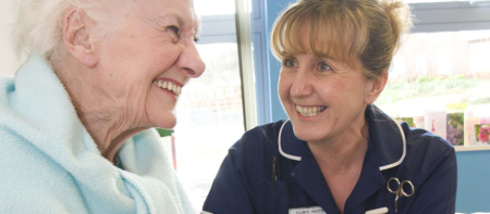 A nurse smiling with an elderly patient.