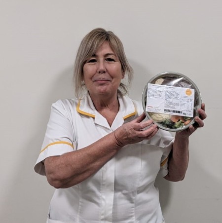 A photograph of a woman holding up a packet of food.