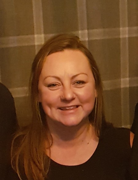 A woman with brown hair, smiling.