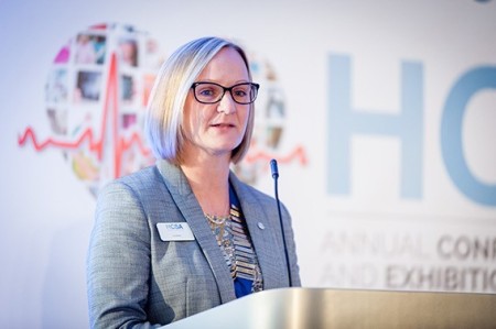 Helen Lisle standing behind a podium giving a speech