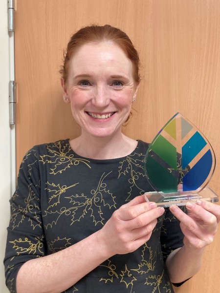 A woman smiling holding an award.