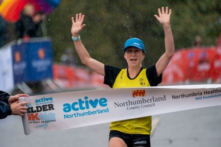 A female running and crossing the finish line.