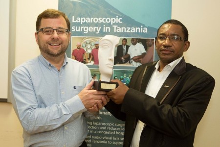 Two people holding an award in front of a banner saying laparoscopic surgery.