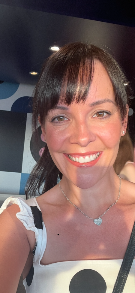 Lady with dark brown hair wearing a polka dot dress smiling to the camera