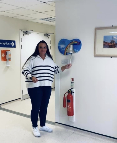 Woman wearing a white striped top ringing a bell