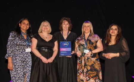 Five women. One of them is holding an award.