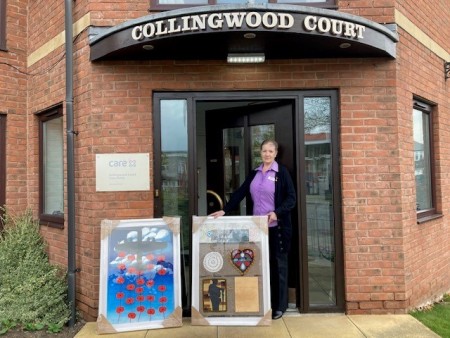 A woman standing the doorway to a care home. She has two pieces of art with her.