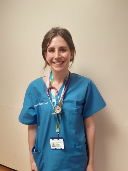 A woman with brown hair wearing blue scrubs.