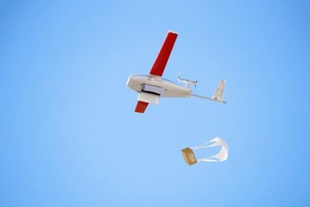 A Zipline drone flying and dropping a parcel with a parachute.
