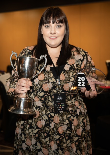 A woman holding a trophy and an award.