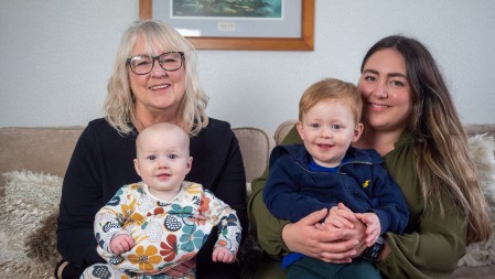 Two women holding a baby and a toddler.