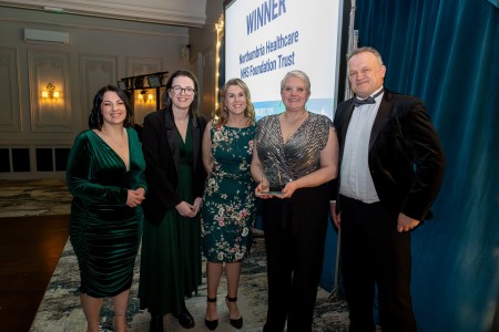 A group of five people from the Health and Care Academy and apprenticeship team smiling for a photograph holding an award