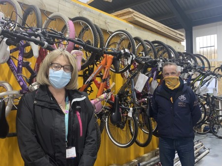 A man and a woman standing in front of bikes that are hanging on the wall.