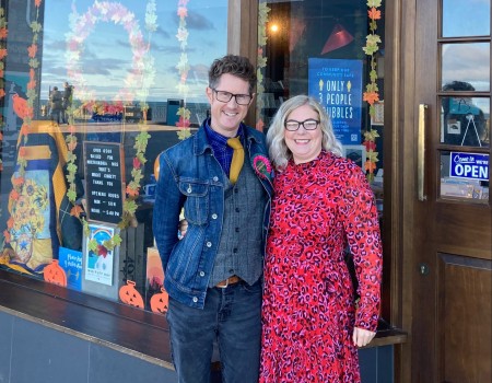 A photograph of a man and a woman outside a shop.