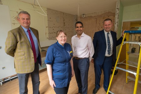 Four people in a room that is under construction. There is a ladder on the right.