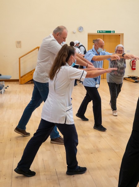 A group of people doing stretches alongside a male and female physio.