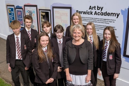 A group of students standing in front of their artwork with one of the trust's directors