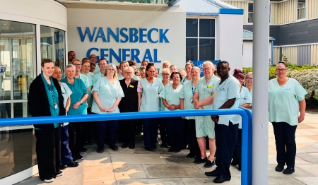 Group of workers wearing green scrubs standing in front of Wansbeck General Hospital.