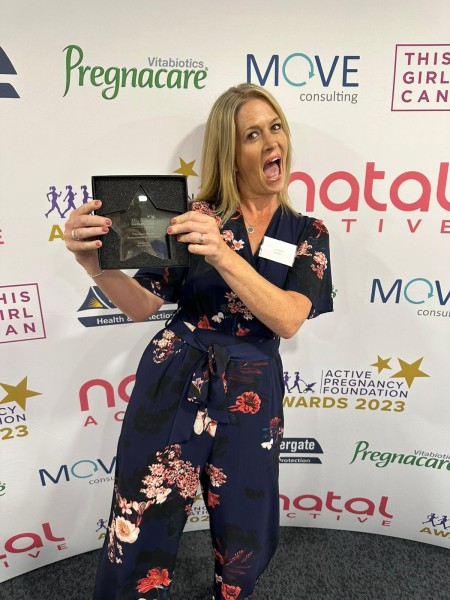 A woman smiling with an award.