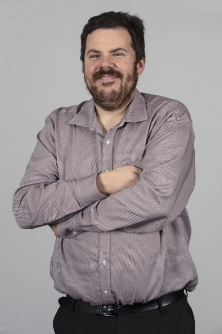 A man with dark hair and a beard.