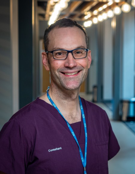 A portrait of a man in scrubs.